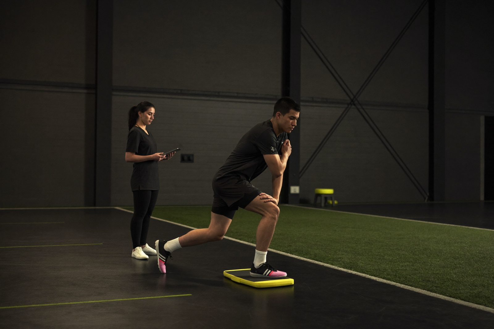 Futbolista realizando una sentadilla a una pierna sobre plataforma de fuerza en el gimnasio de readaptación